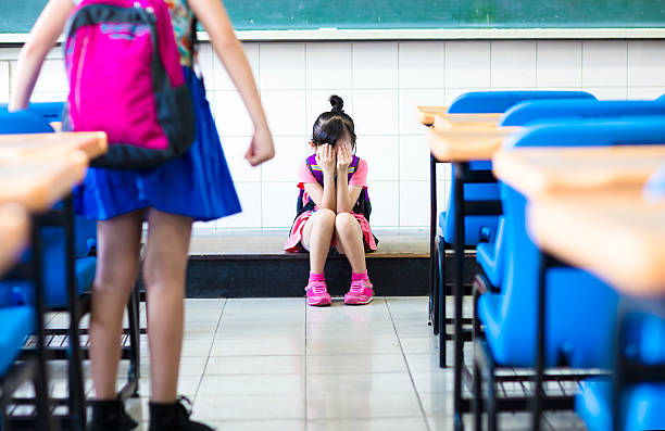intimidation petite fille à l'école en configuration salle de classe - anger child furious asian ethnicity photos et images de collection