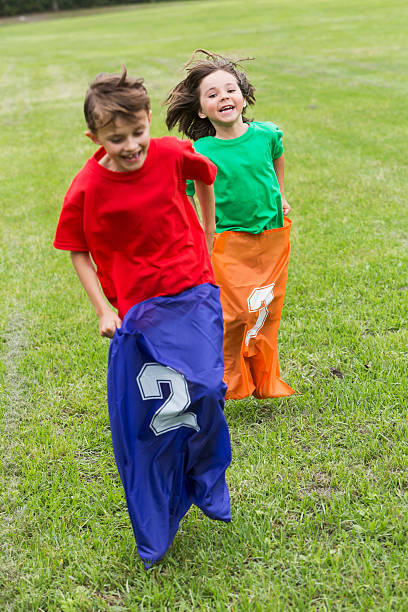 двух мальчиков, конкурирующих в картофель бег в мешках - child playing sack race sports race стоковые фото и изображения