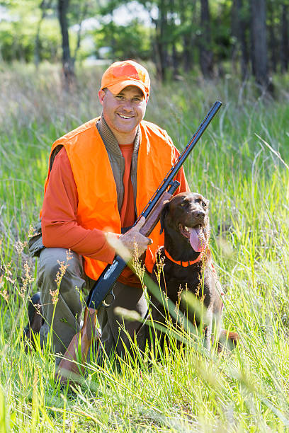 istock Man hunting with shotgun kneeling next to retriever 486032934