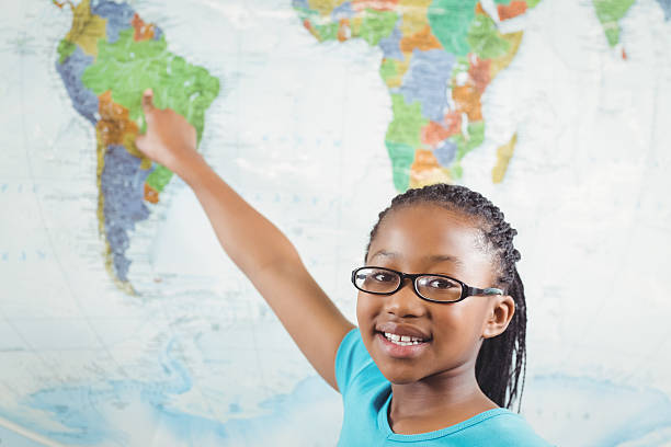 Portrait of smiling pupil pointing on world map in a classroom in school