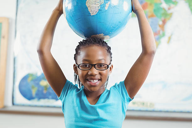 istock Smiling pupil holding globe in front of world map 486033620