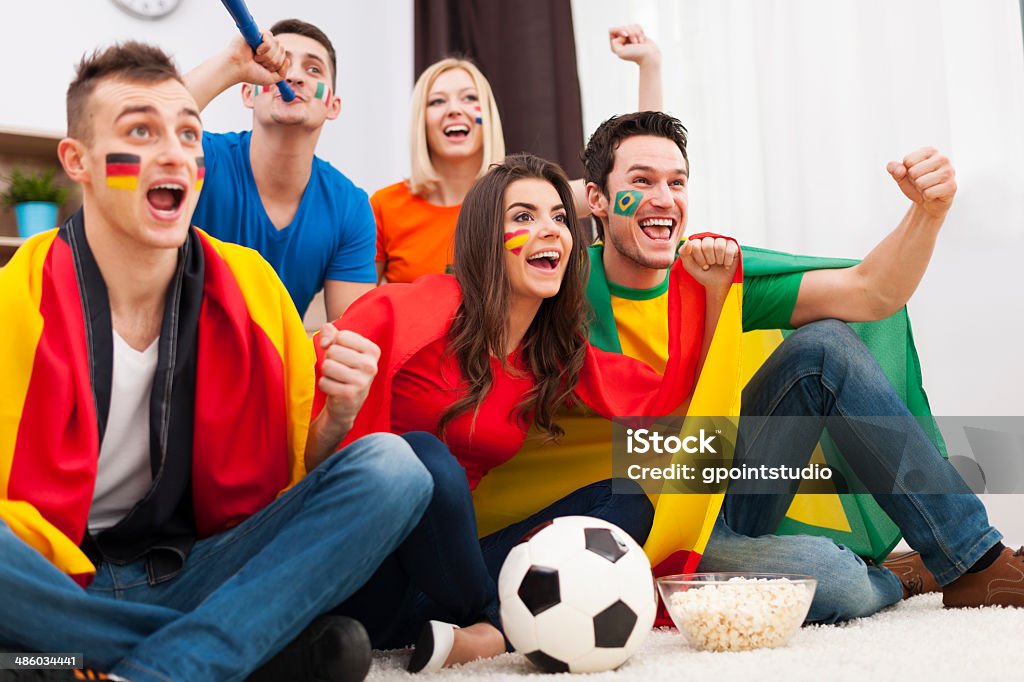 Группа международных людям радость футбольный матч дома - Стоковые фото Американский футбол - мяч роялти-фри