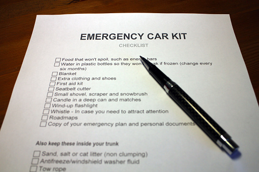 Someone filling out Emergency Car Kit Checklist.