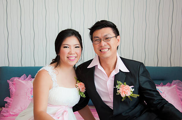 istock Bride and groom sit on pink bed smiling to camera 486041782