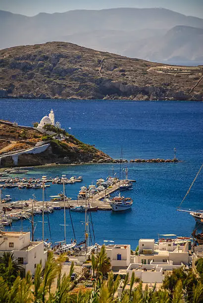 The natural Harbour / Port of Ios, Greece with Fishing and Sailing Boats. Little Greek Church and the Port town of Ios.