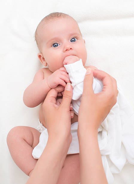istock Cute little baby  getting dressed by mother. 486055396
