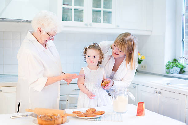 面白い幼児の女の子焼くアップルパイ、彼女 grandmothers - great grandchild ストックフォトと画像