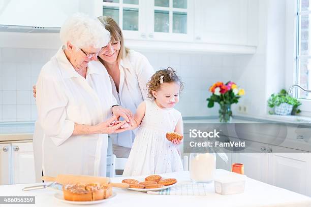 Happy Woman Baking Cake With Senior Mother And Toddler Daughter Stock Photo - Download Image Now