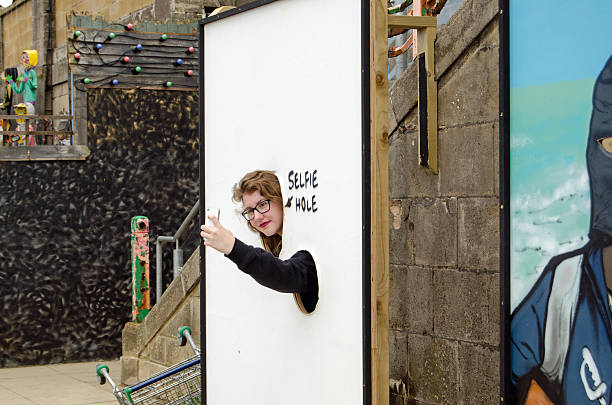 Dismaland Selfie cut out Weston-Super-Mare, UK - August 26, 2015:  A visitor makes use of the selfie-hole parody of a traditional seaside photo opportunity at Dismaland in Weston-Super-Mare Somerset.  The Somerset resort has become very popular thanks to the work of Banksy and other artists. banksy stock pictures, royalty-free photos & images