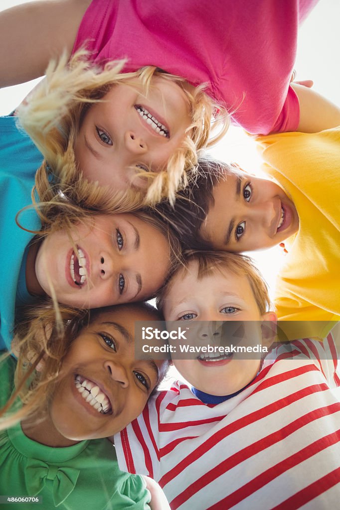 Smiling classmates with arms around looking down to camera Portrait of smiling classmates with arms around looking down to camera on campus Child Stock Photo