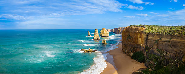The Twelve Apostles seastacks panorama Australia Panoramic image of morning light on the landmark Twelve Apostles along the Great Ocean Road in Victoria, Australia. There is some cloud in the blue sky and the sea reflects a turquoise colour. great ocean road photos stock pictures, royalty-free photos & images