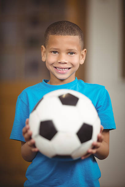 istock Smiling pupil holding football in a classroom 486063438