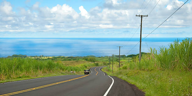 空の道路を車でハワイの丘陵地帯と海 ストックフォト