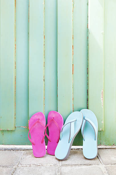Family vacation with 4 pairs of beach flip-flops leaning against the wall.