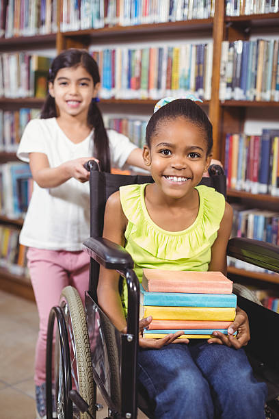 istock Smiling pupil in wheelchair holding books 486073706