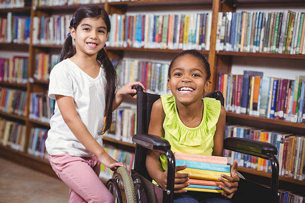 uśmiechająca się uczeń w inwalidzkim, trzymając książki - child at library zdjęcia i obrazy z banku zdjęć