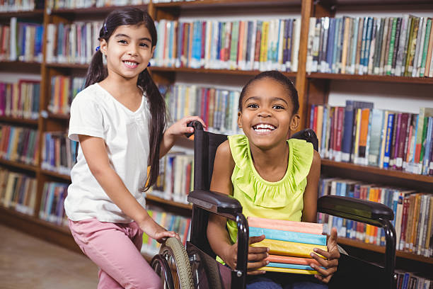 улыбающаяся учащихся в инвалидной коляске, держа книги - child at library стоковые фото и изображения