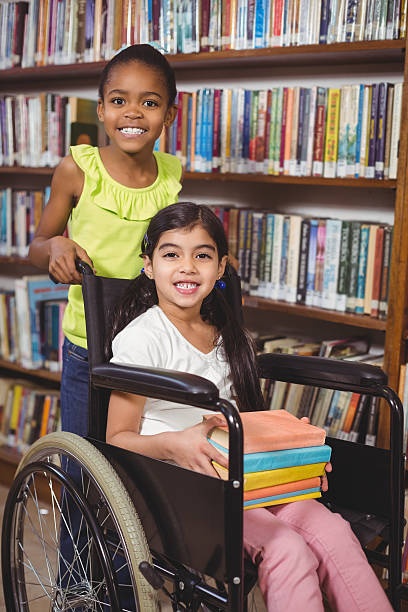istock Smiling pupil in wheelchair holding books 486073786