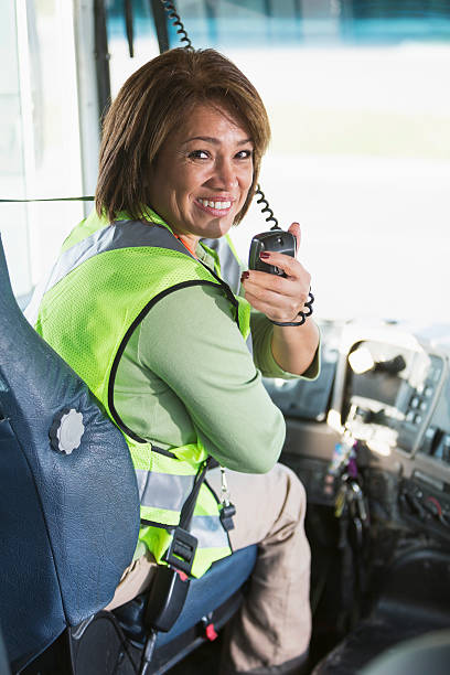 Female bus driver Hispanic woman (50 years) driving a school bus. vehicle interior audio stock pictures, royalty-free photos & images