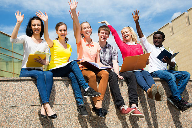 istock Excited students with arms outstretched outdoors 486077398