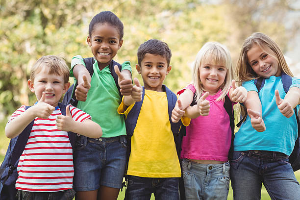 camarades de classe souriants faisant thumbs up à caméra - hand sign human hand ok sign grass photos et images de collection