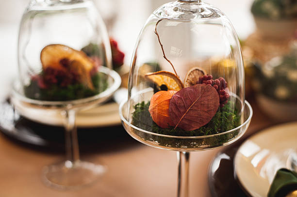 Fresh strawberries dipped in dark chocolate next to a vase with a white flower bouquet in a cozy room