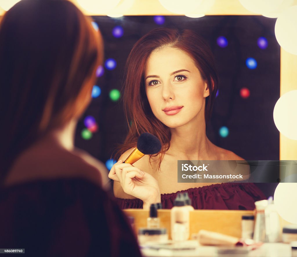 Portrait of a beautiful woman as applying makeup Portrait of a beautiful woman as applying makeup near a mirror. Photo in retro color style. 2015 Stock Photo