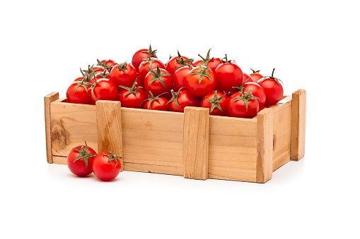 Organic cherry tomatoes in a small wooden crate sitting on white background. DSRL studio photo taken with Canon EOS 5D Mk II and Canon EF 70-200mm f/2.8L IS II USM Telephoto Zoom Lens
