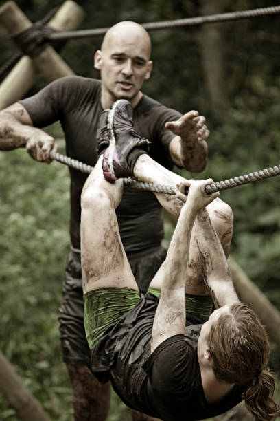 istock man helping woman to cross an rope obstacle 486095250