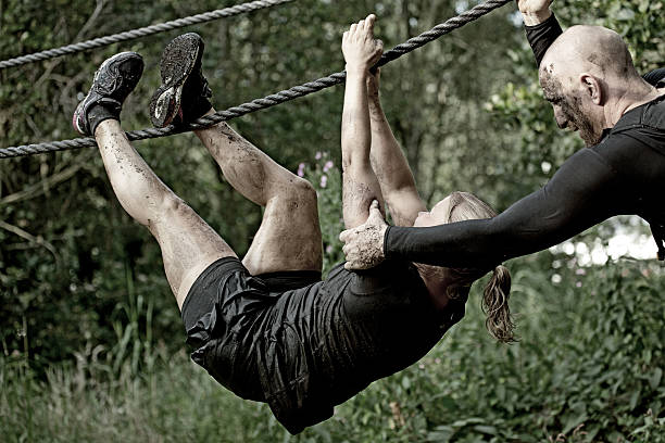 istock man helping woman to cross an rope obstacle 486095292