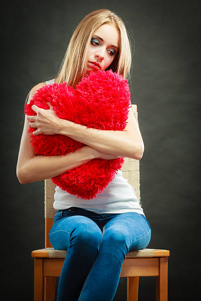 istock Sad unhappy woman holding red heart pillow 486105028