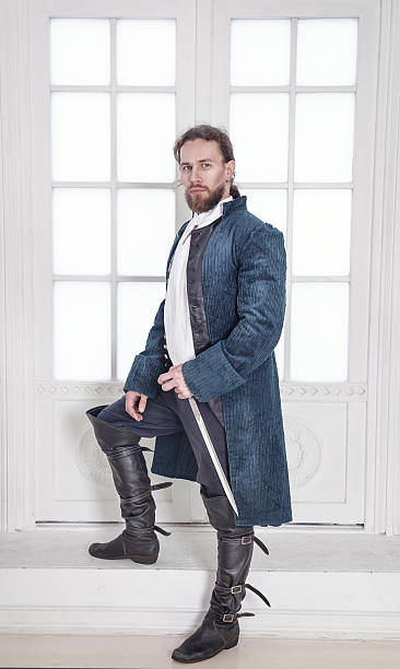 Young handsome man in medieval clothes with sword standing stock photo