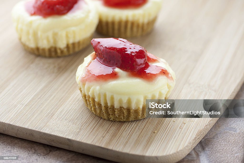 Mini Strawberry Cheesecake Mini strawberry cheesecake on a bamboo cutting board. Candy Stock Photo