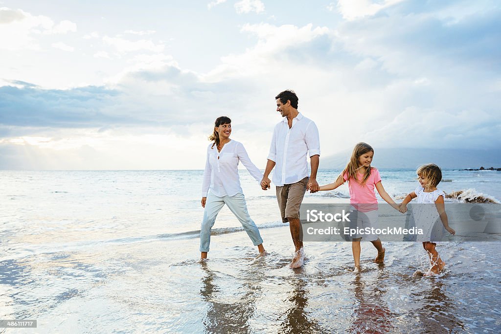 Happy young family walking on the beach Happy young family walking on the beach at sunset. Happy Family Lifestyle Family Stock Photo