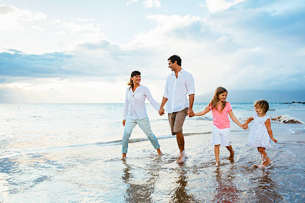 Happy young family walking on the beach stock photo