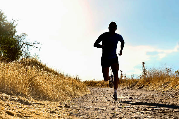 istock front silhouette sport man running cross country at summer sunset 486132278