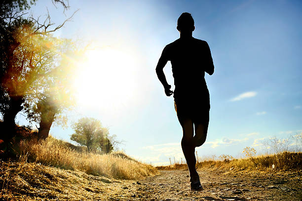 istock front silhouette sport man running cross country at summer sunset 486132286
