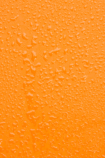 Raindrops background. Close up. Ice cold,  Orange surface covered with water drops condensation texture. 