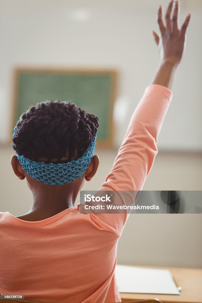 Rear view of pupil raising hand in a classroom Rear view of pupil raising hand in a classroom in school 2015 Stock Photo