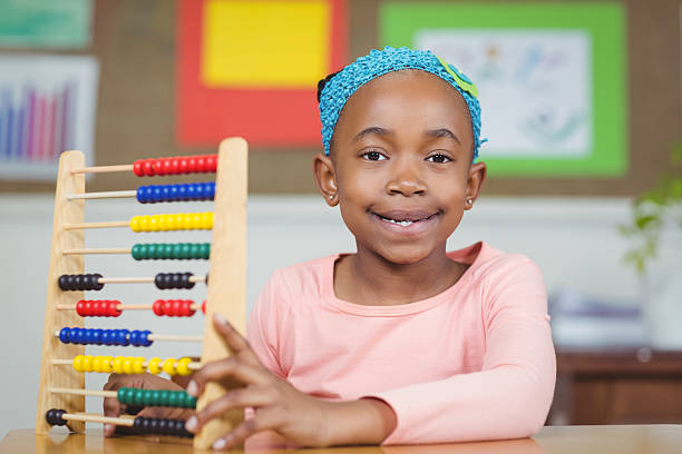 istock Smiling pupil calculating with abacus in a classroom 486138780