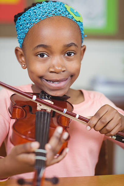 istock Smiling pupil playing violin in a classroom 486138788