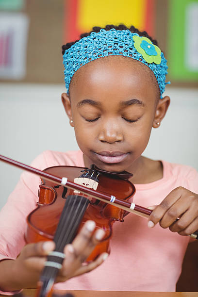 istock Focused pupil playing violin in a classroom 486138790