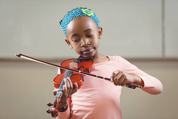istock Focused pupil playing violin in a classroom 486138794