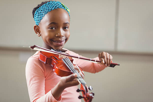 istock Smiling pupil playing violin in a classroom 486138802