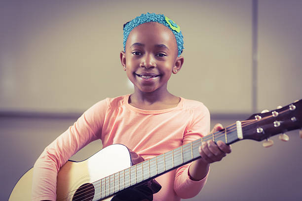 istock Smiling pupil playing guitar in a classroom 486138810