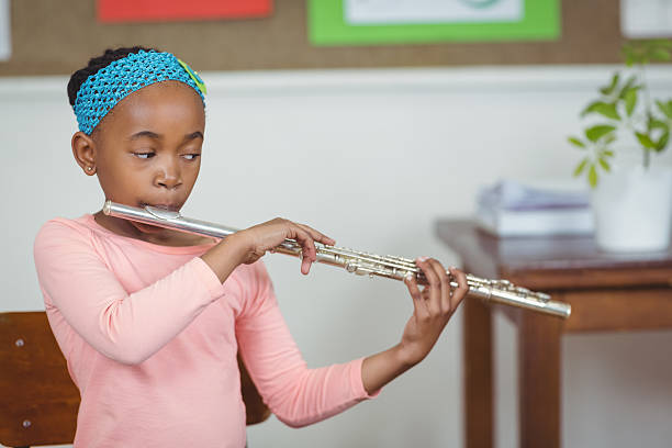 istock Cute pupil playing flute in a classroom 486138850