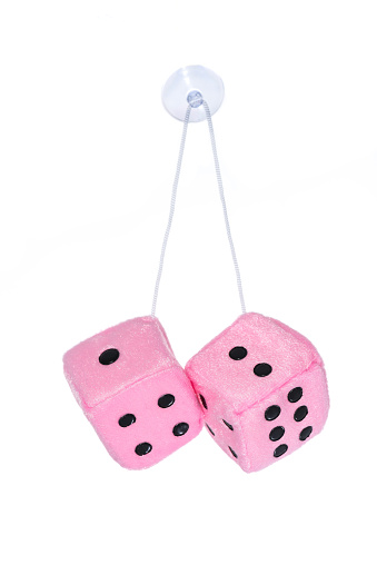 Two pink furry dice intended to hang from a car windscreen - studio shot with a white background