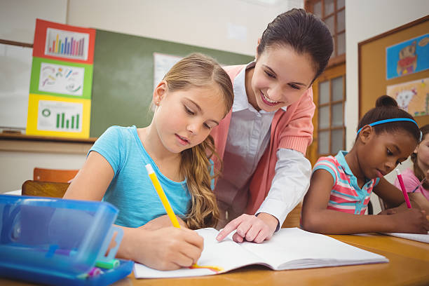 istock Pupil and teacher at desk in classroom 486140114