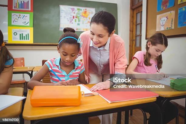 Pupil And Teacher At Desk In Classroom Stock Photo - Download Image Now - 18-19 Years, 2015, 6-7 Years