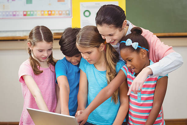 istock Teacher and pupils looking at laptop 486144870